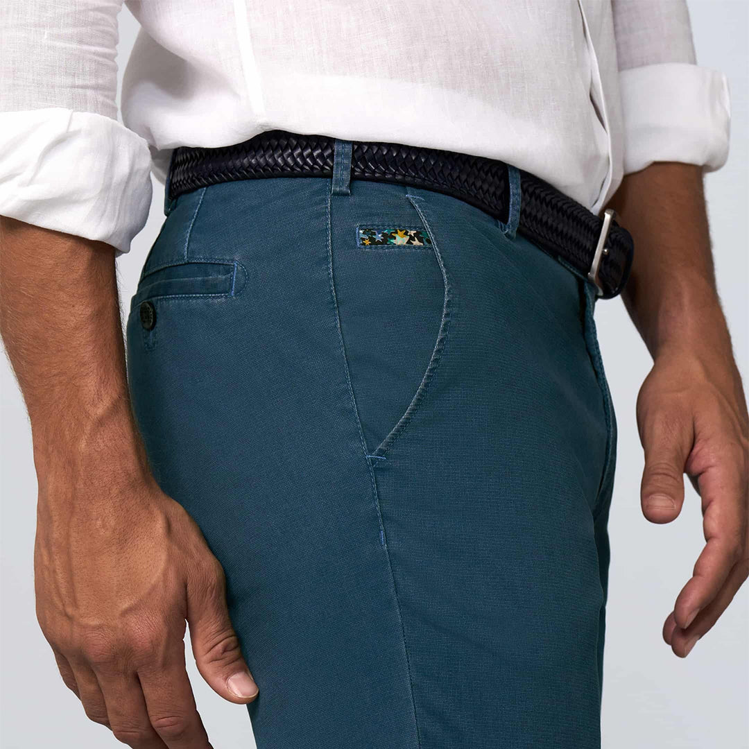 Person wearing blue pants with a belt and white shirt on a light gray background