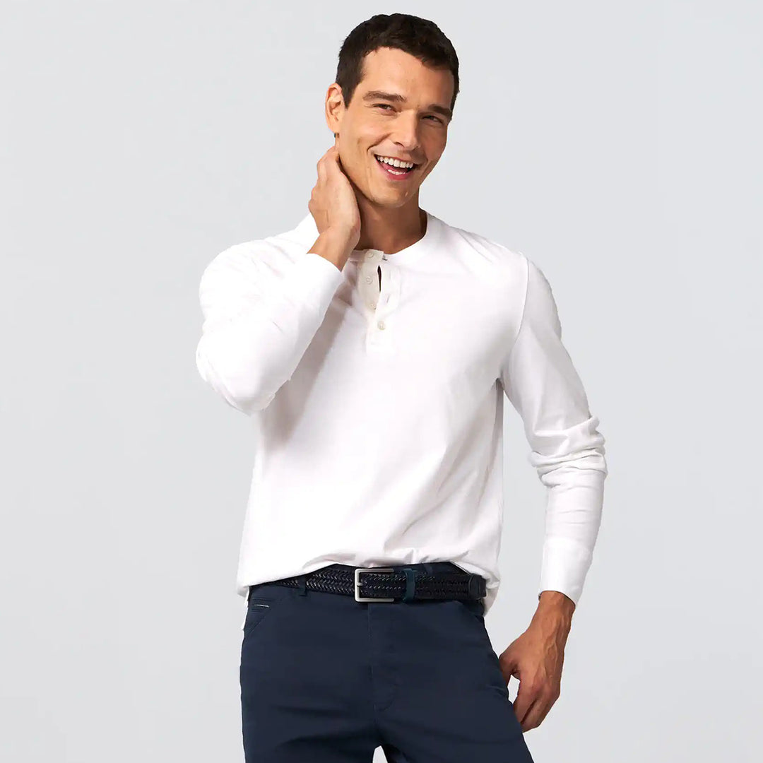 Man wearing a white long-sleeve shirt and navy pants on a light gray background
