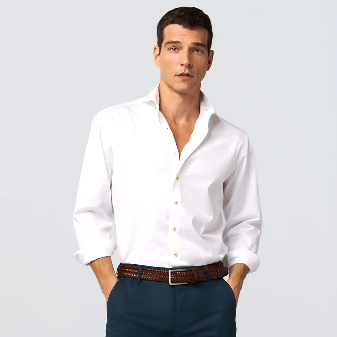 Man wearing a white dress shirt and dark pants on a light gray background