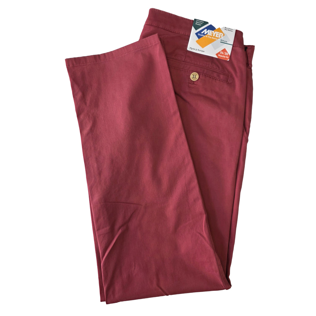 Folded maroon pants with a label on a white background