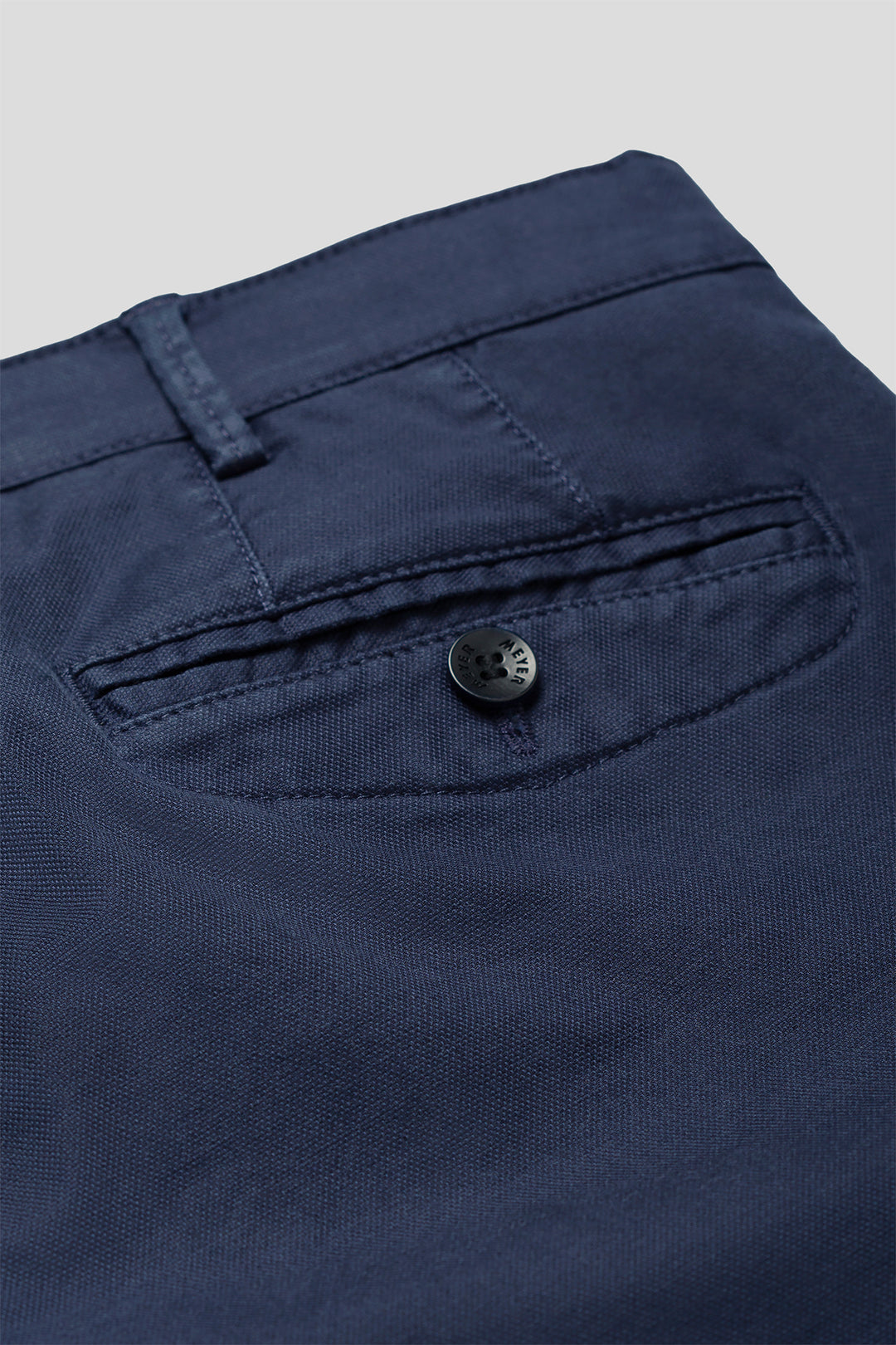 Close-up of a navy blue button on a garment with a light gray background