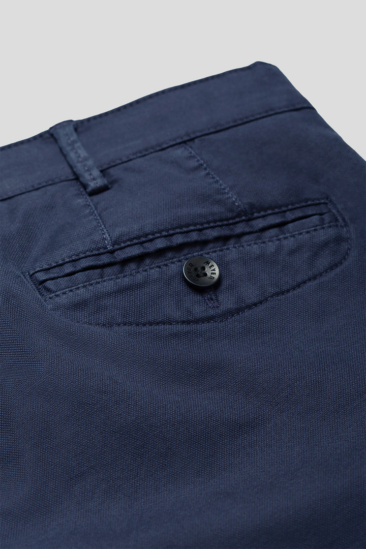 Close-up of a navy blue button on a garment with a light gray background